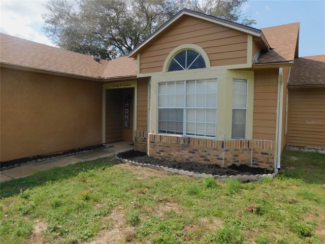 2618 Coventry Ln, Ocoee, FL 34761 - property entrance featuring a shingled roof, a yard, and brick siding