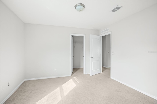 unfurnished bedroom with light carpet, a closet, and a spacious closet