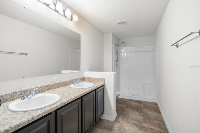 bathroom featuring vanity, a textured ceiling, toilet, and walk in shower