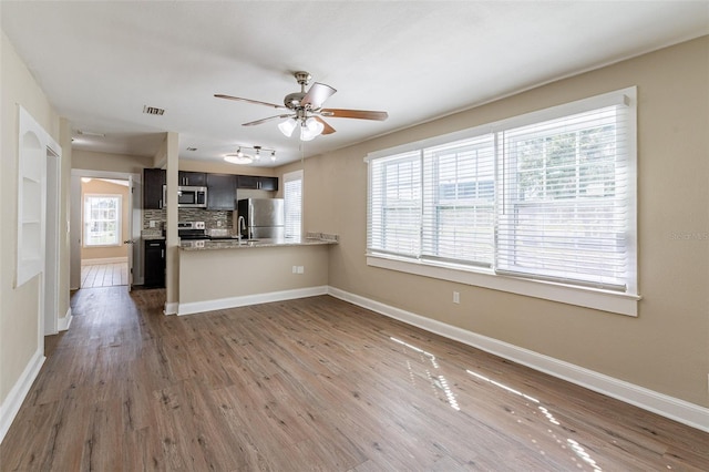 kitchen featuring kitchen peninsula, stainless steel appliances, dark hardwood / wood-style floors, and plenty of natural light