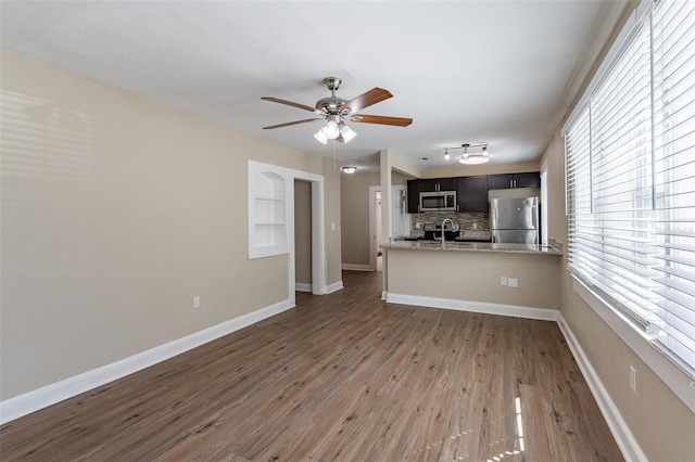 unfurnished living room with sink, ceiling fan, dark hardwood / wood-style floors, and plenty of natural light