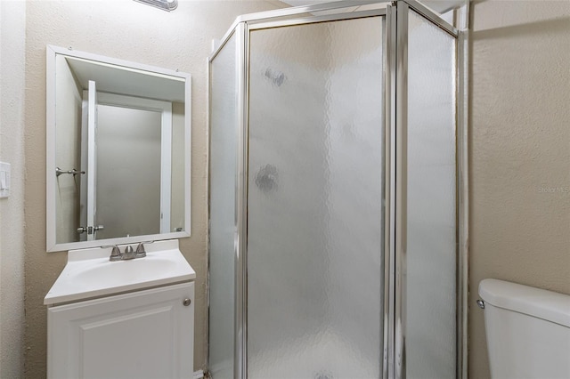 bathroom with vanity, toilet, and a shower with door