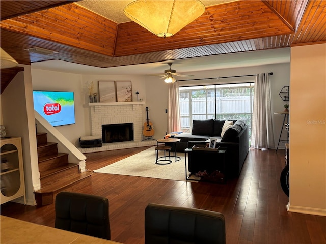 living room featuring stairway, a brick fireplace, wooden ceiling, and dark wood-style flooring