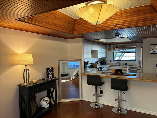 kitchen with dark wood-type flooring, decorative light fixtures, wood ceiling, appliances with stainless steel finishes, and a sink