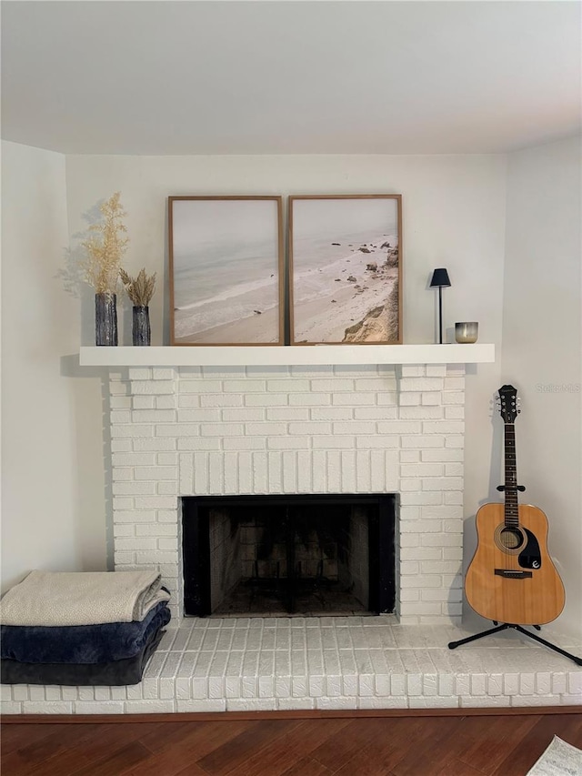 details featuring a brick fireplace and wood finished floors