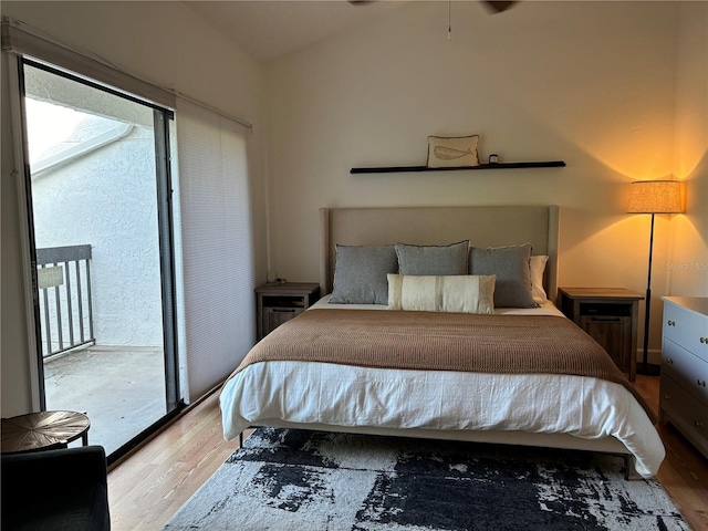 bedroom featuring access to exterior, lofted ceiling, and wood finished floors