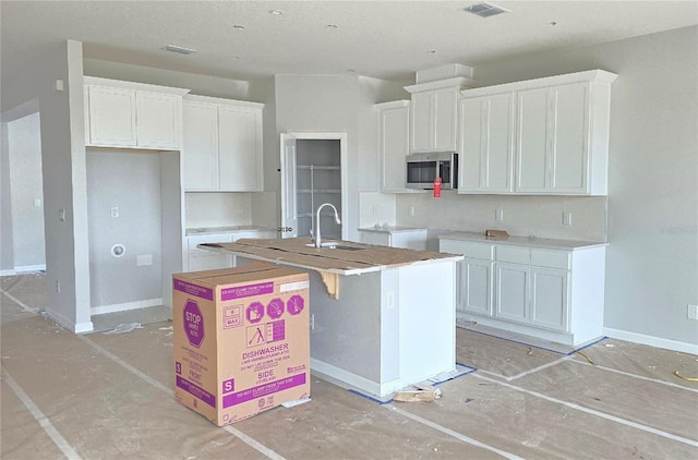 kitchen featuring sink, a center island with sink, and white cabinets