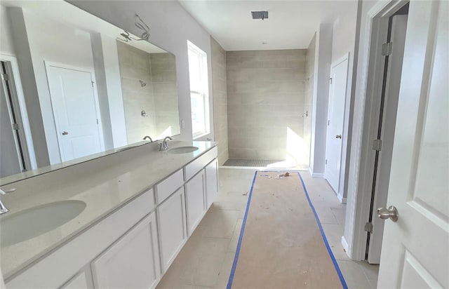 bathroom with tiled shower and vanity