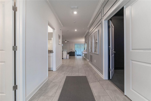 hallway with ornamental molding and light tile patterned flooring