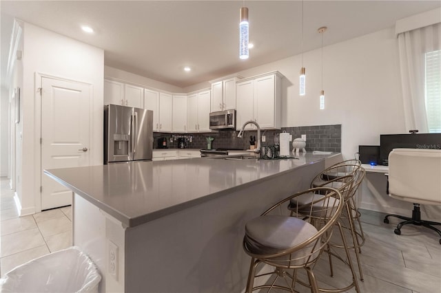 kitchen with kitchen peninsula, white cabinets, stainless steel appliances, and pendant lighting