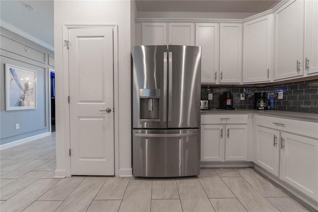 kitchen with white cabinetry, crown molding, decorative backsplash, and stainless steel fridge