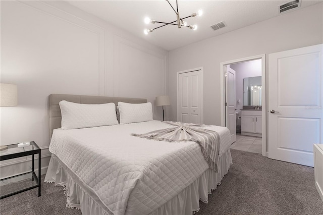 bedroom featuring connected bathroom, a closet, carpet floors, and an inviting chandelier