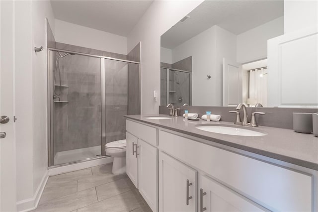 bathroom with a shower with door, vanity, toilet, and tile patterned flooring