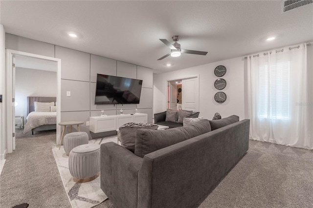 living room featuring a textured ceiling, light colored carpet, and ceiling fan