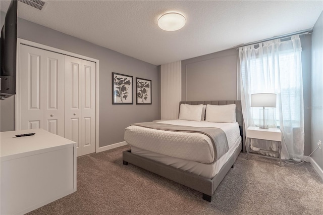 bedroom featuring a closet, a textured ceiling, and dark carpet