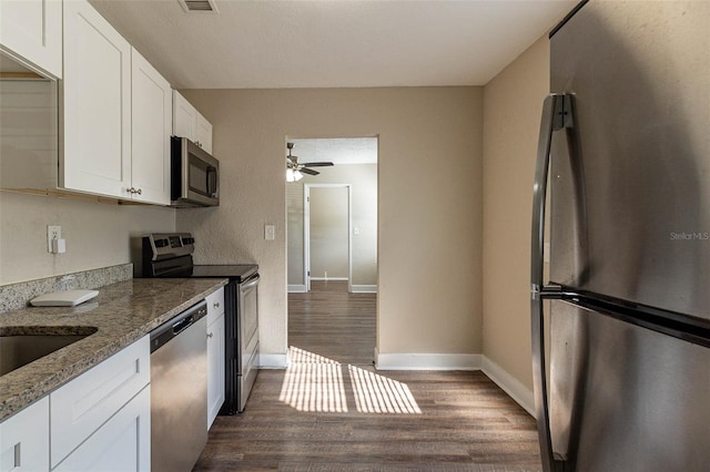 kitchen featuring appliances with stainless steel finishes, ceiling fan, dark hardwood / wood-style floors, stone counters, and white cabinets