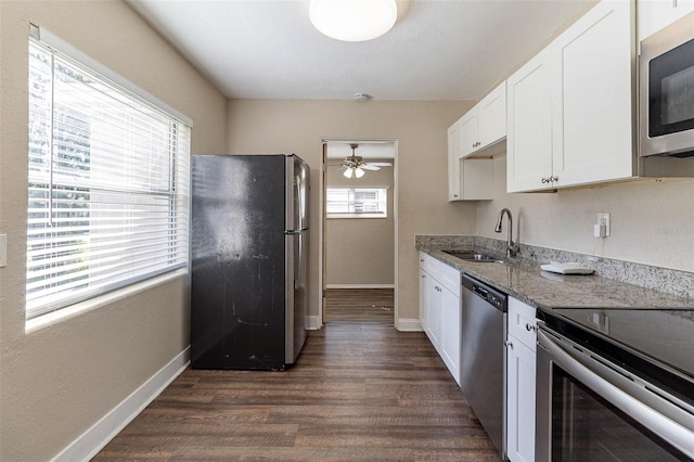 kitchen with dark stone counters, white cabinetry, appliances with stainless steel finishes, dark hardwood / wood-style flooring, and sink