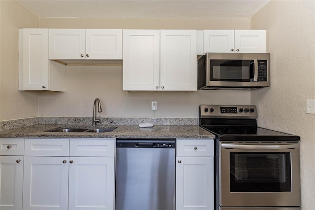 kitchen featuring dark stone countertops, white cabinetry, sink, and stainless steel appliances