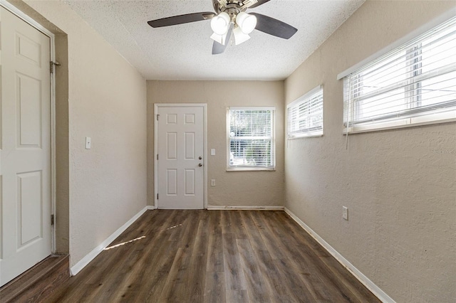 spare room featuring dark wood-type flooring, ceiling fan, and a textured ceiling