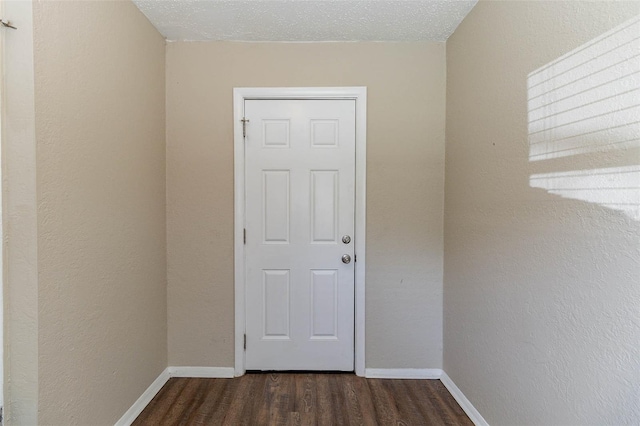 doorway featuring dark wood-type flooring and a textured ceiling