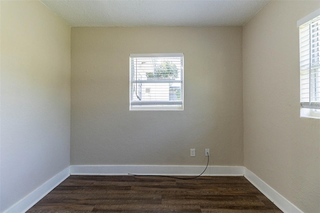 unfurnished room featuring a textured ceiling, dark hardwood / wood-style flooring, and a healthy amount of sunlight