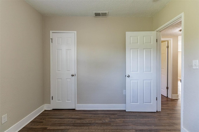 unfurnished bedroom featuring dark hardwood / wood-style floors and a textured ceiling