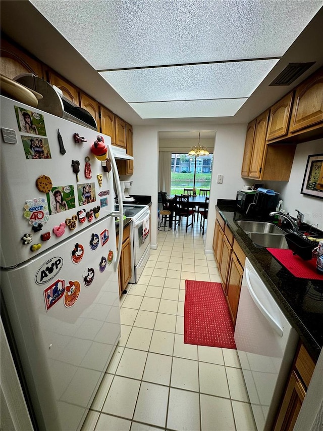 kitchen featuring white appliances, a notable chandelier, light tile patterned floors, and sink