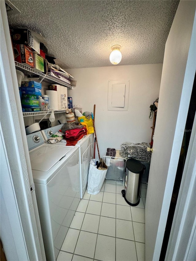 laundry room featuring electric panel, a textured ceiling, light tile patterned flooring, and separate washer and dryer