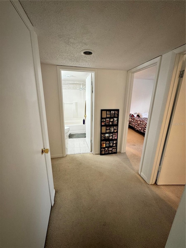 hall featuring light carpet and a textured ceiling