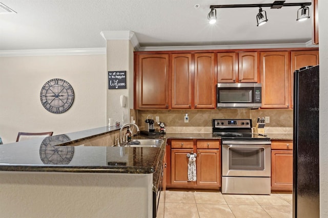 kitchen featuring kitchen peninsula, tasteful backsplash, appliances with stainless steel finishes, dark stone counters, and sink