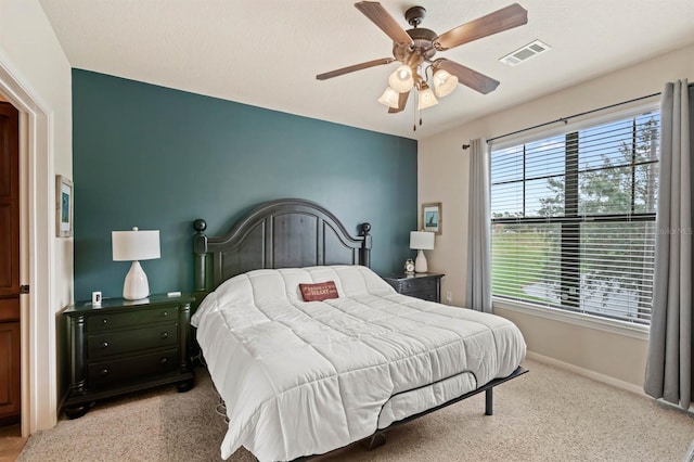 bedroom with baseboards, light carpet, a ceiling fan, and visible vents