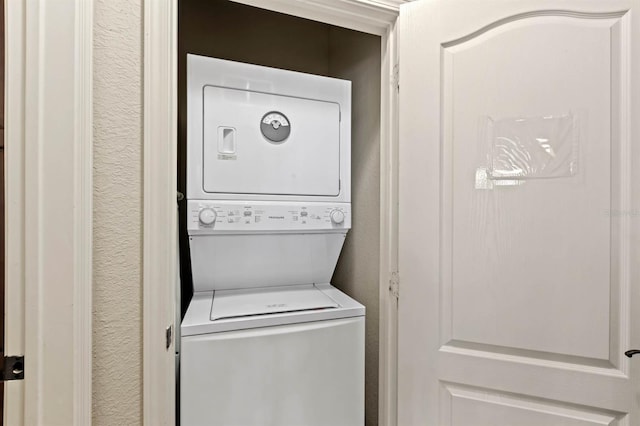 laundry room featuring laundry area, stacked washing maching and dryer, and a textured wall