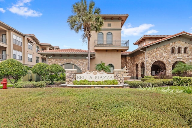 view of front of property featuring a front yard and a balcony