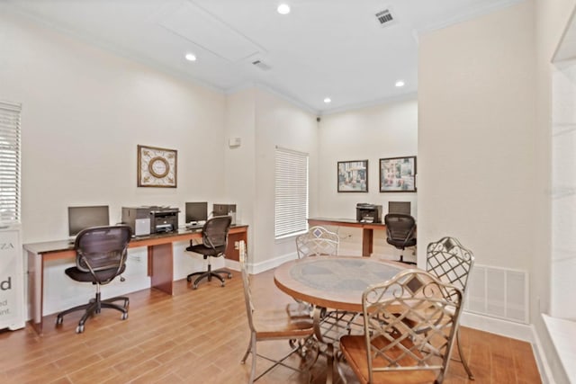 dining room featuring built in desk, crown molding, and light hardwood / wood-style flooring