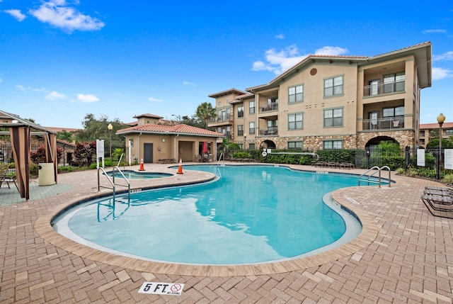 community pool with a patio and fence