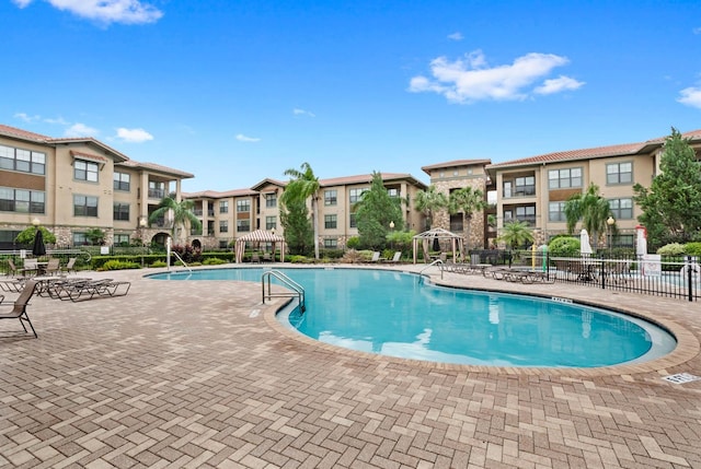 community pool featuring fence, a patio area, and a residential view