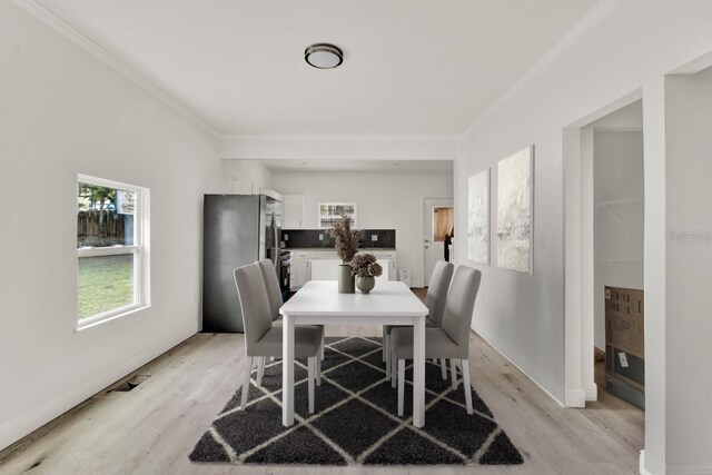 dining area with light wood-type flooring and ornamental molding