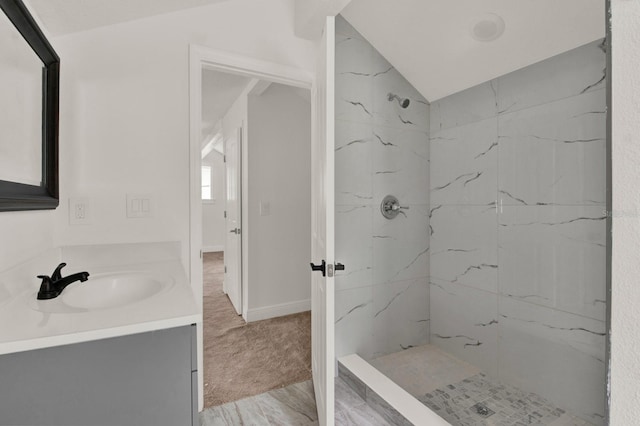 bathroom featuring wood-type flooring, vanity, a tile shower, and vaulted ceiling