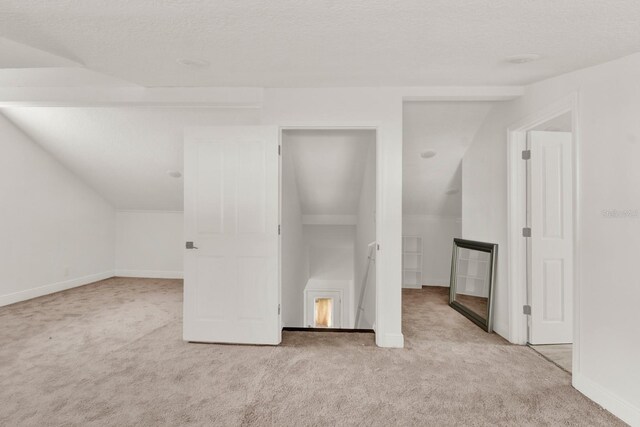 bonus room featuring a textured ceiling, light carpet, and lofted ceiling