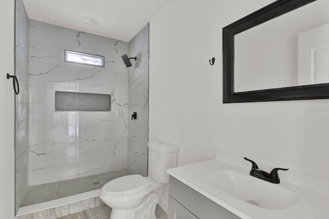 bathroom featuring a tile shower, vanity, hardwood / wood-style flooring, and toilet