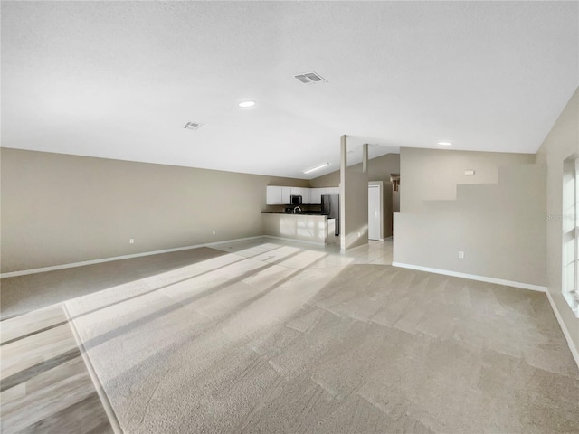 unfurnished living room with light carpet and lofted ceiling