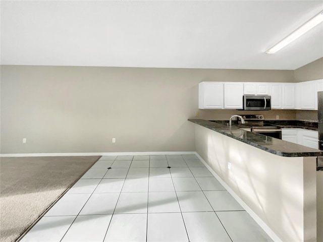 kitchen featuring appliances with stainless steel finishes, kitchen peninsula, light carpet, dark stone counters, and white cabinets