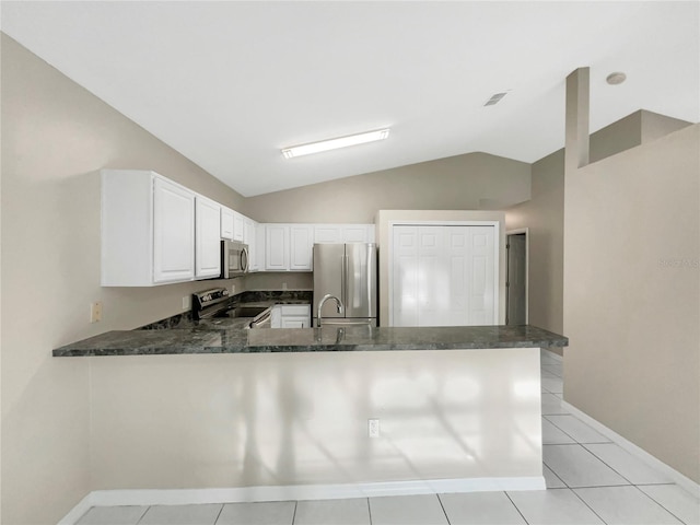 kitchen featuring kitchen peninsula, stainless steel appliances, vaulted ceiling, light tile patterned floors, and white cabinetry