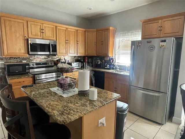 kitchen featuring dark stone countertops, black appliances, light tile patterned floors, and a kitchen island