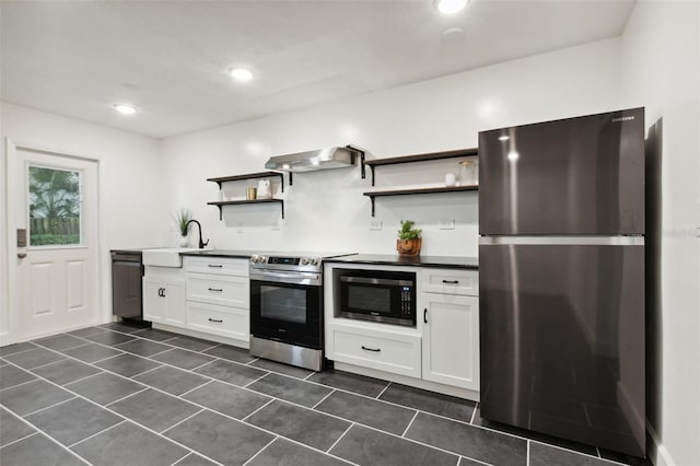 kitchen with dark tile patterned floors, range hood, sink, white cabinets, and appliances with stainless steel finishes