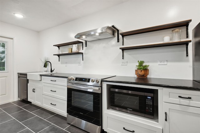 kitchen with appliances with stainless steel finishes, white cabinetry, dark tile patterned floors, sink, and ventilation hood