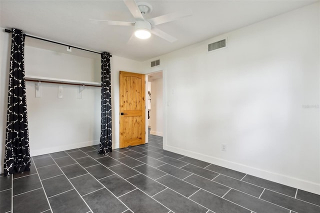 unfurnished bedroom featuring dark tile patterned floors, a closet, and ceiling fan