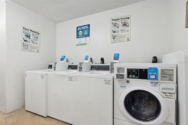 laundry room featuring light colored carpet, a textured ceiling, and washing machine and clothes dryer