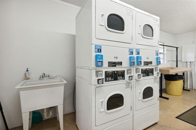 clothes washing area featuring a textured ceiling, stacked washer / drying machine, and washing machine and clothes dryer