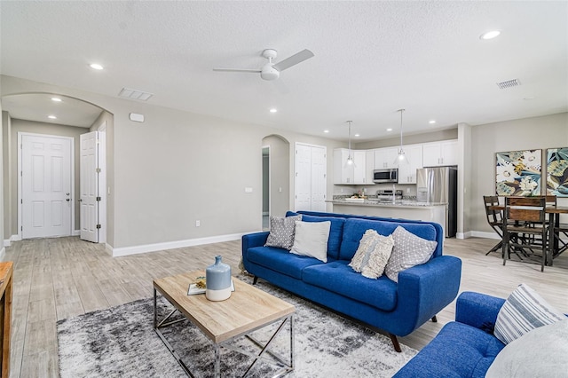 living room featuring a textured ceiling, light hardwood / wood-style floors, and ceiling fan